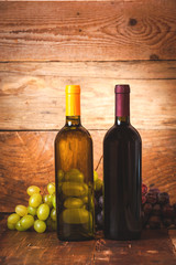 Obraz premium Red and white wine bottle with grapes and barrel on wooden rusti