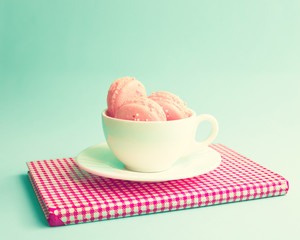 Pink macaroons in a tea cup and vintage book