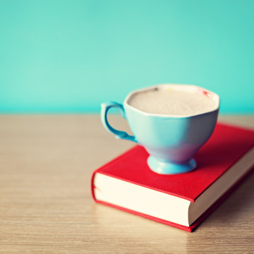 Vintage blue tea cup over a red book