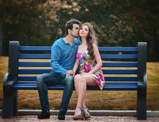 Young couple in love sitting together on the bench in the park