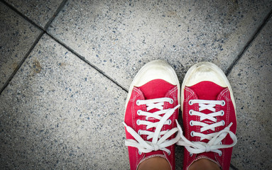 Feet in red sneaker on concrete floor