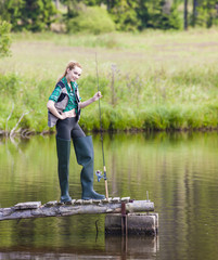 young woman fishing on pier at pond