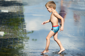 Little boy walking  in puddle