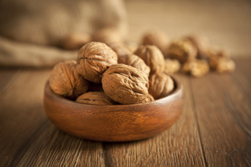 Walnut kernels and whole walnuts on rustic old wooden table