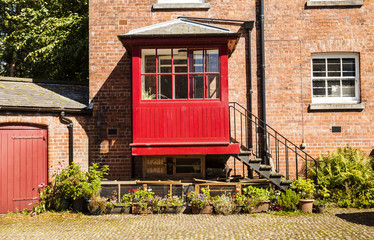 Courtyard with redbrick house and iron steps leading to a red po