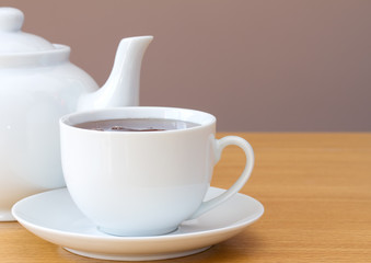 Cup of tea with teapot on a table