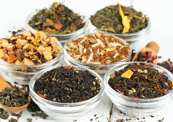 assortment of dry tea in glass bowls on wooden surface