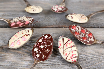 Spoons with tasty chocolate for party on old wooden table
