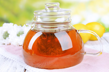 Teapot with tea on table on bright background