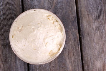 Fresh homemade butter in bowl, on color wooden background