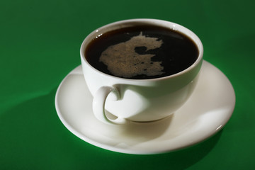 Cup of coffee on green background