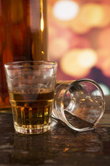 glass of rum whiskey over defocused lights background