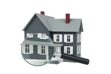 A magnifying glass examining a miniature model home.