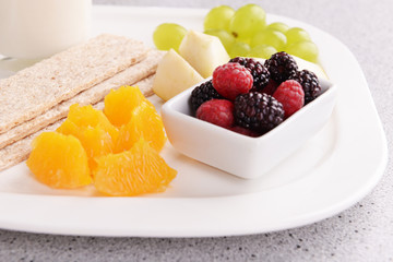 Slices of fruits with crispbreads and glass of milk