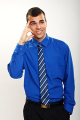 Thinking young smiling businessman in blue shirt