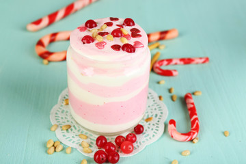 Cranberry milk dessert in glass jar, on color wooden background