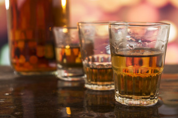 shots of rum whiskey over defocused lights background