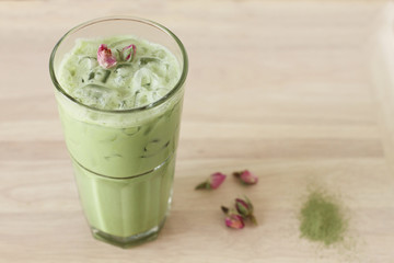 green tea latte with dried rose on wooden background