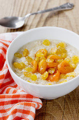 Porridge with raisin, dried apricots and honey in a white bowl