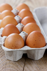Chicken eggs in a carton box on a wooden rustic table