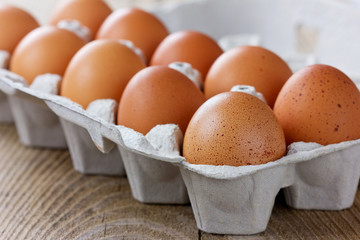 Chicken eggs in a carton box on a wooden rustic table