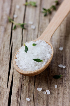 Sea salt in spoon with a fresh herbs thyme
