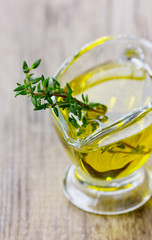 Olive oil with fresh thyme on a wooden rustic board