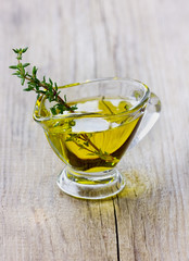 Olive oil with fresh thyme on a wooden rustic board