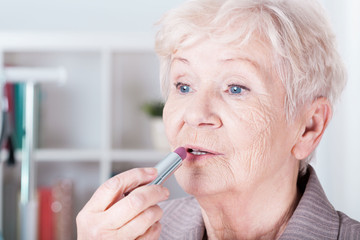 Senior woman applying lipstick