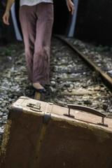 Woman and vintage suitcase on railway road