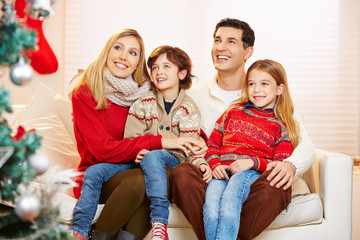 Kinder sitzen bei Eltern auf dem Schoß zu Weihnachten