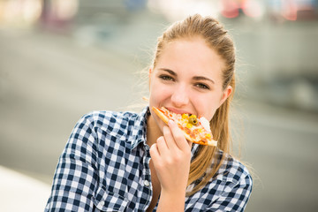 Teenager eating pizza in street