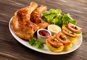 Barbecued chicken legs with French fries and vegetables