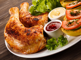 Barbecued chicken legs with French fries and vegetables