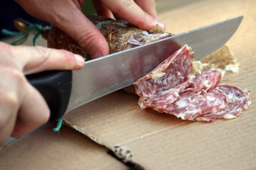 MAN slicing the salami with sharp knife