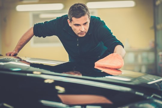 Man Worker Polishing Car On A Car Wash