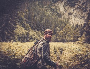 Man with hiking equipment walking in mountain forest