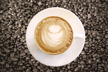 Hot Cappuccino with white cup on coffee beans