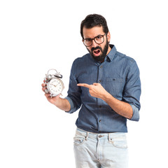 Surprised young hipster man holding a clock