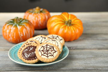 Tasty Halloween cookies on plate, on wooden table
