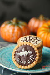 Tasty Halloween cookies on plate, on decorative spiderweb