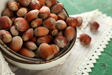 Hazelnuts on plate on napkin on wooden background