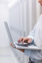 Mid section of a technician typing on his notebook
