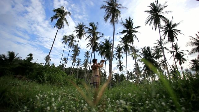 Woman takes pictures of palm trees in the jungle on Koh Samui.