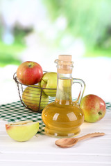 Apple cider vinegar in glass bottle and ripe fresh apples,