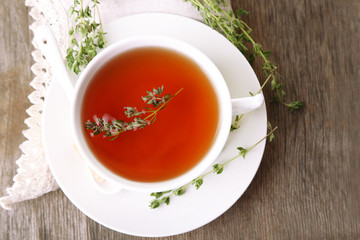 Cup of tasty herbal tea with thyme on wooden table