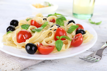 Spaghetti with tomatoes, olives and basil leaves