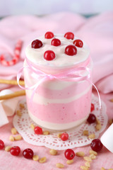 Raspberry milk dessert in glass jar, on color wooden background