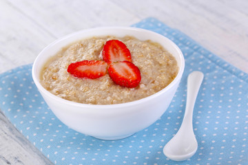 Tasty oatmeal with strawberry on table close-up