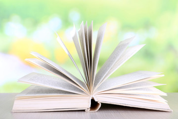 Open book on wooden table on natural background